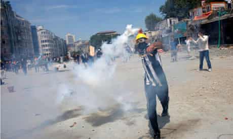 A protester throws a teargas cannister back at riot police in Taksim Square
