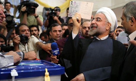 Iranian presidential candidate Hassan Rouhani raises his identity card before casting his vote