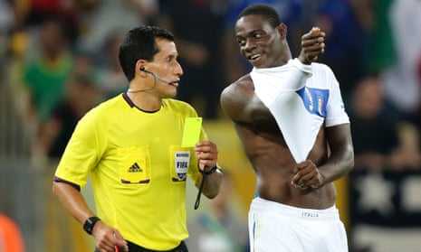 Referee Enrique Osses of Chile shows a yellow card to Italy's Mario Balotelli.