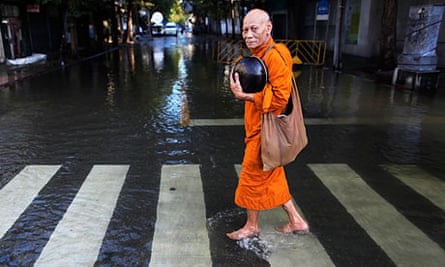 A Buddhist monk walks in a flooded street to collect alms outside the Grand Palace in Bangkok
