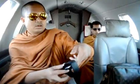 Screengrab from YouTube of monk with aviator sunglasses, branded travel bag and wireless headphones