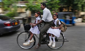 School run: a Sri Lankan ethnic Tamil man rides his children to a school in a morning in Colombo, Sri Lanka.