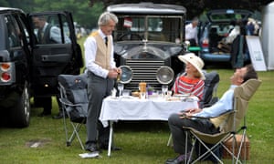 Helen Cook, Guy Baird and Nick Cook from London enjoy a picnic in front of a 1925 Baby Rolls Royce ahead of day two of the Royal Ascot meeting at Ascot Racecourse, UK.