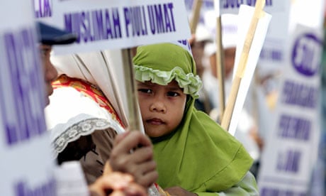 A girl rests in her mother's arms during a protest in Jakarta