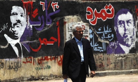 A man walks past graffiti depicting Egyptian President Mohamed Morsi 