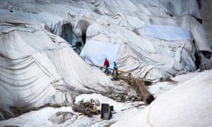 People entering the grotto of the Rhone glacier in the central Alps of Switzerland. The glacier is protected by blankets at this time of the year to keep ice melting to a minimum.