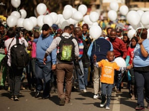 People carry 95 balloons, to mark Nelson Mandela's upcoming 95th birthday, as they march and sing outside the Medi-Clinic Heart Hospital