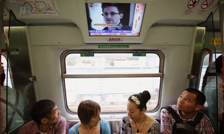Passengers on a train in Hong Kong watch a TV showing news on Edward Snowden, the US whistleblower. 