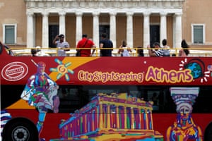 Tourists take photographs from the top of a tourist bus, of protesters taking part in an anti- austerity rally (not seen in the picture) outside the Greek parliament in central Athens,