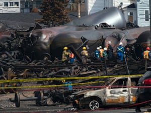 Worker stand by damaged tanker cars, as work continues at the crash site of the train derailment and fire in Lac-Megantic, Quebec.