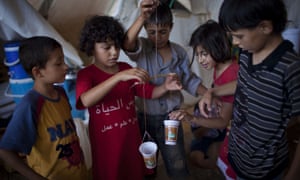 Syrian refugee children play with makeshift weighing scales at the Bab al-Salam refugee camp in Syria's northern city of Azaz.