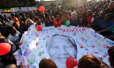 Well-wishers hold a giant banner with an image of Nelson Mandela