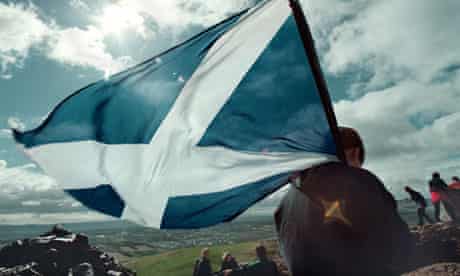 A young Scot bearing the saltire looks down on to Edinburgh from Arthur's Seat