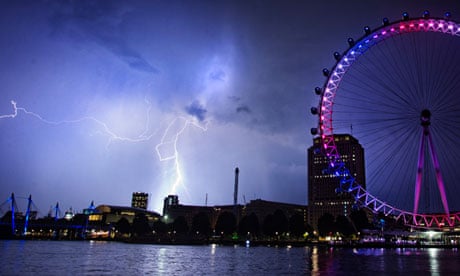 Lightning strikes behind the London Eye, which is red, white and blue to celebrate the royal baby