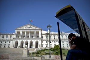A man waits at a bus stop in front of the Portuguese Parliament in Lisbon on July 3, 2013.
