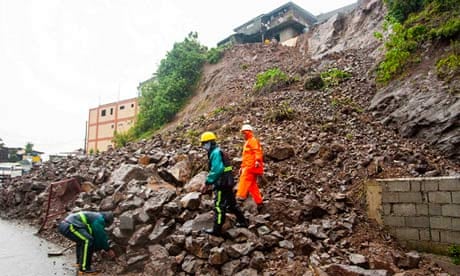 Workers clear debris from a road after a landslide caused by typhoon Utor in the Philippines