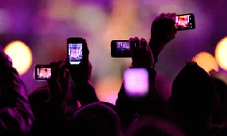 Audience takes photos with their mobile phones during a gig