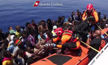 Italian coastguards help immigrants out of their boat off the coast of Lampedusa