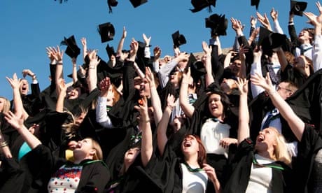 A group of university students graduating on graduation day, throwing their caps in the air, UK