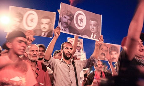 Tunisian demonstrators hold pictures of assassinated opposition leader Mohamed Brahmi