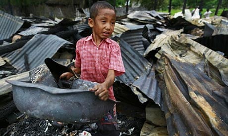 A boy salvages belongings amid a burnt-out house in Htan Kone village, Burma.