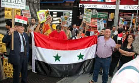 Anti war protesters carry the Syrian flag as they stand near the US Armed Forces Recruiting Center in New York.