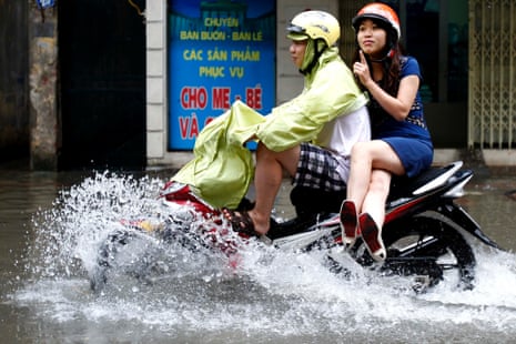 A couple ride a motorcycle along a street flooded  from heavy rains caused by tropical storm Mangkhut in Hanoi, Vietnam.