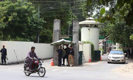 A policeman and security guards monitor activities on a road to the US consulate in Lahore, Pakistan