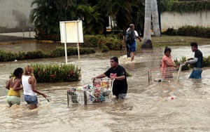 mexico floods: People carry supplies in a flooded street in Acapulco