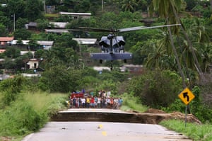 mexico floods: People wait as a helicopter lands on a collapsed road in Coyuca de Benitez