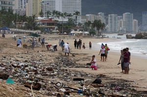mexico floods: Tourists walk on a beach in Acapulco covered in debris