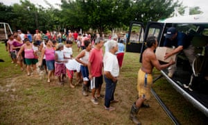 Villagers line up before a helicopter from Mexico's Attorney General's Office to get aid after their community was affected by the rains and floods caused by Tropical Storm Manuel in San Jeronimo, Mexico.