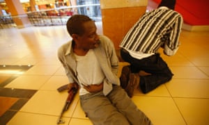 An injured policeman holds on to his wound as his compatriot searches through the Westgate shopping centre for gunmen in Nairobi.