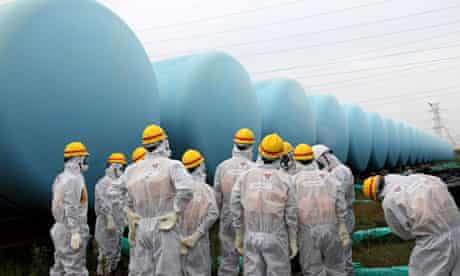 Staff of Japan's nuclear regulator near storage tanks for radioactive water at Fukushima Daiichi