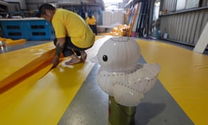 A worker arranges yellow PVC tarpaulin next to a miniature duck model at a factory where the "Rubber Duck" inflatable floating sculpture by Dutch conceptual artist Florentijn Hofman is being constructed in Taipei.