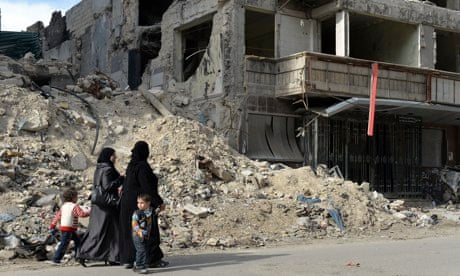 Syrian women and children walk past ruins in Aleppo, April 2013