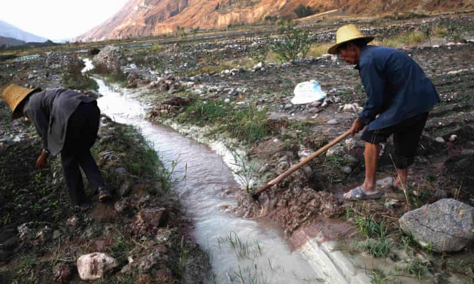 Farmers dig ditches to lead water from a white polluted stream into farm fields, in Dongchuan district of Kunming, Yunnan province