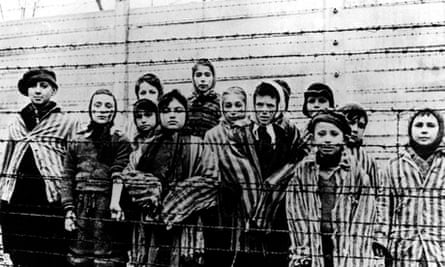 A group of children in striped concentration camp uniforms behind barbed wire fencing at Auschwitz
