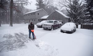 Mike Cushman wears a head-mounted light as he shovels his driveway at sunrise in Norfolk, Massachusetts.