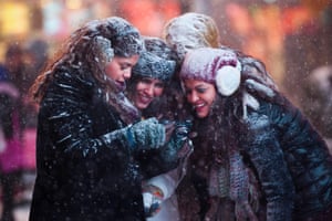 Tourists look at a camera to see photographs they took of themselves in a snowstorm in Times Square, New York.