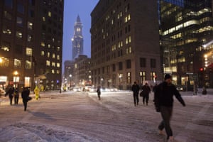 Commuters hurry through an intersection in Downtown Boston after heavy snowfall.