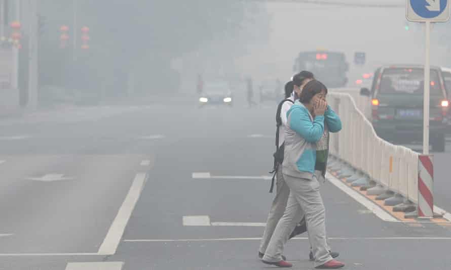 Pedestrians covering their faces as they cross a street in Beijing amid heavy smog.