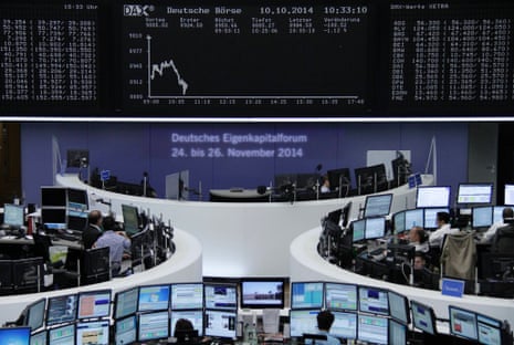 Traders are pictured at their desks in front of the DAX board at the Frankfurt stock exchange October 10, 2014.