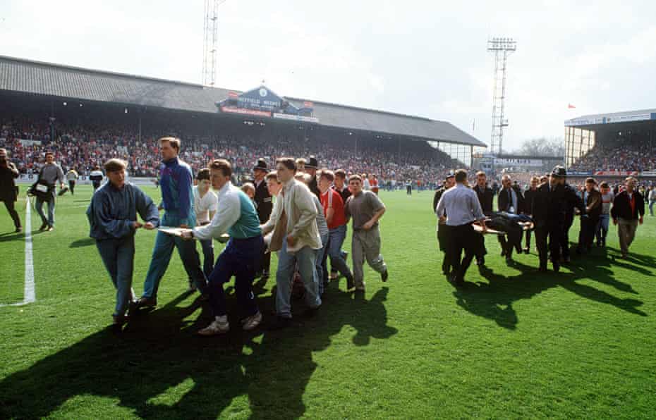 Supporters use advertising boards to carry injured fans out of Hillsborough stadium. The police clai