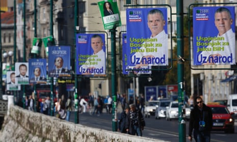 A Bosnian woman passes by election posters  in Sarajevo.