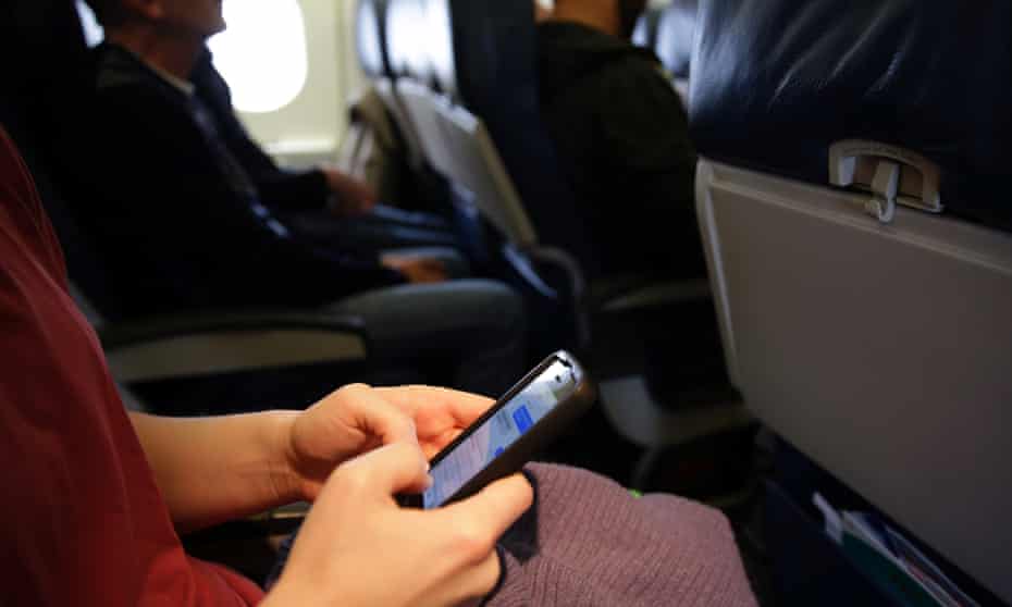 A passenger checks her cellphone before a flight. airplane mobile