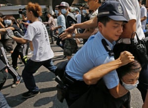 A police officer tries to stop a man removing the metal barricades that protesters have set up to block off main roads. 