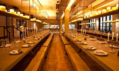 Long communal tables with benches and candles on a hanging shelf at Beast