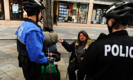 Two Denver police officers from the homeless outreach unit talk to a woman at the 16th Street Mall.