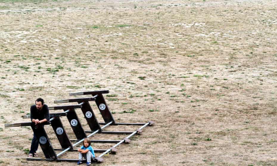 man and child stand in empty sports field 